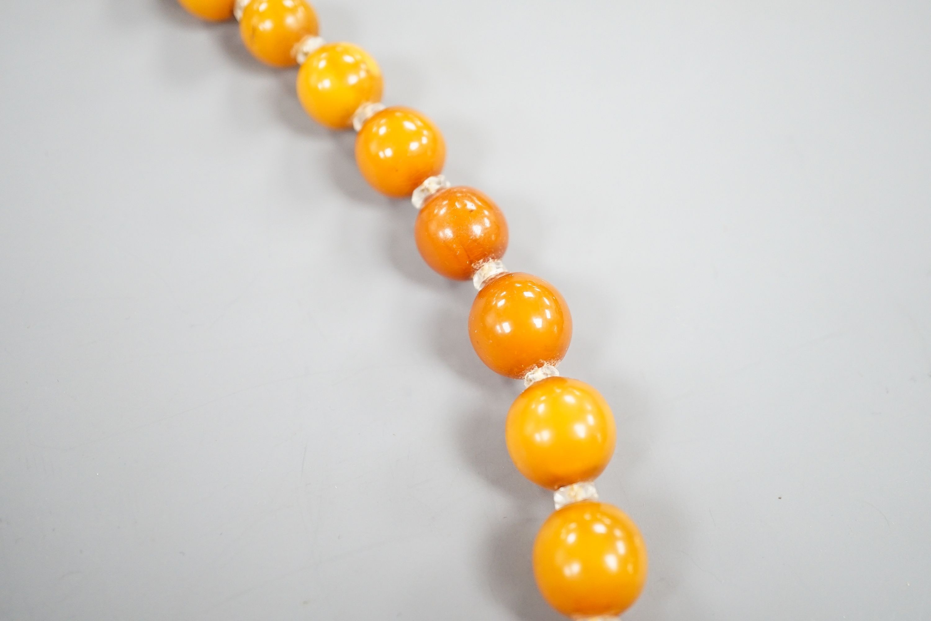 A single strand graduated amber bead necklace, with paste spacers, 42cm, gross weight 31 grams.